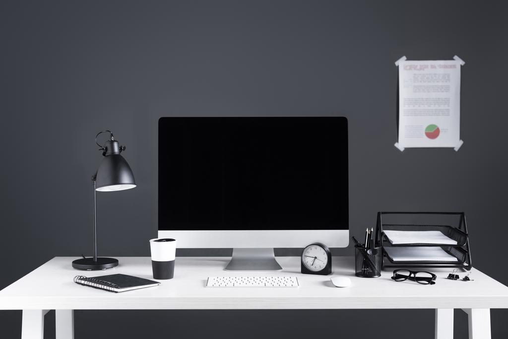 ordinateur de bureau avec écran blanc, tableau d'affaires, horloge et fournitures de bureau sur le lieu de travail
  - Photo, image