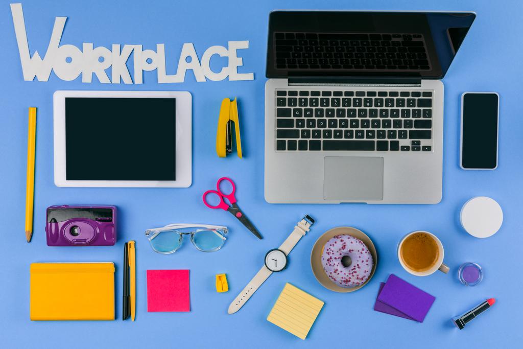 bovenaanzicht van digitale apparaten, inscriptie werkplek en office supplies met donut en koffie op blauw - Foto, afbeelding