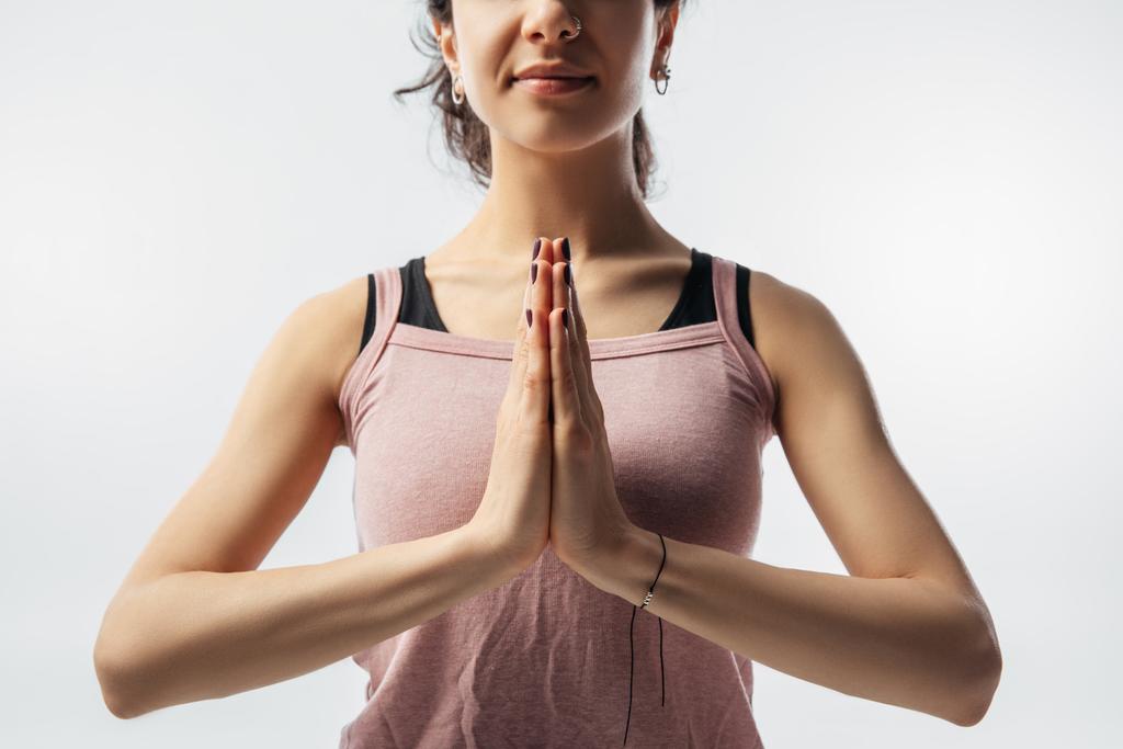 bijgesneden afbeelding van vrouw beoefenen van yoga en zit met de handen in namaste gebaar - Foto, afbeelding