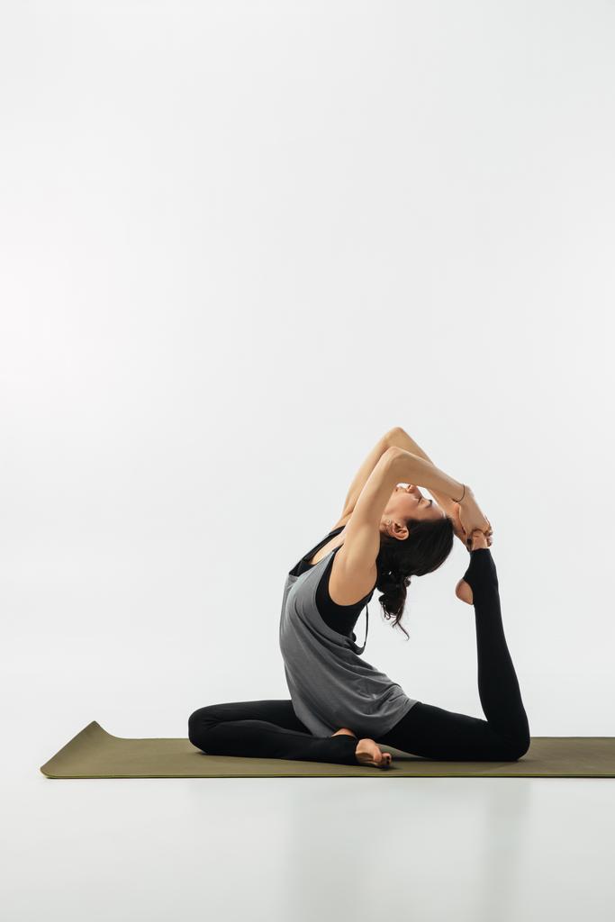 Frau praktiziert Yoga und tut Königstaube isoliert auf weiß - Foto, Bild
