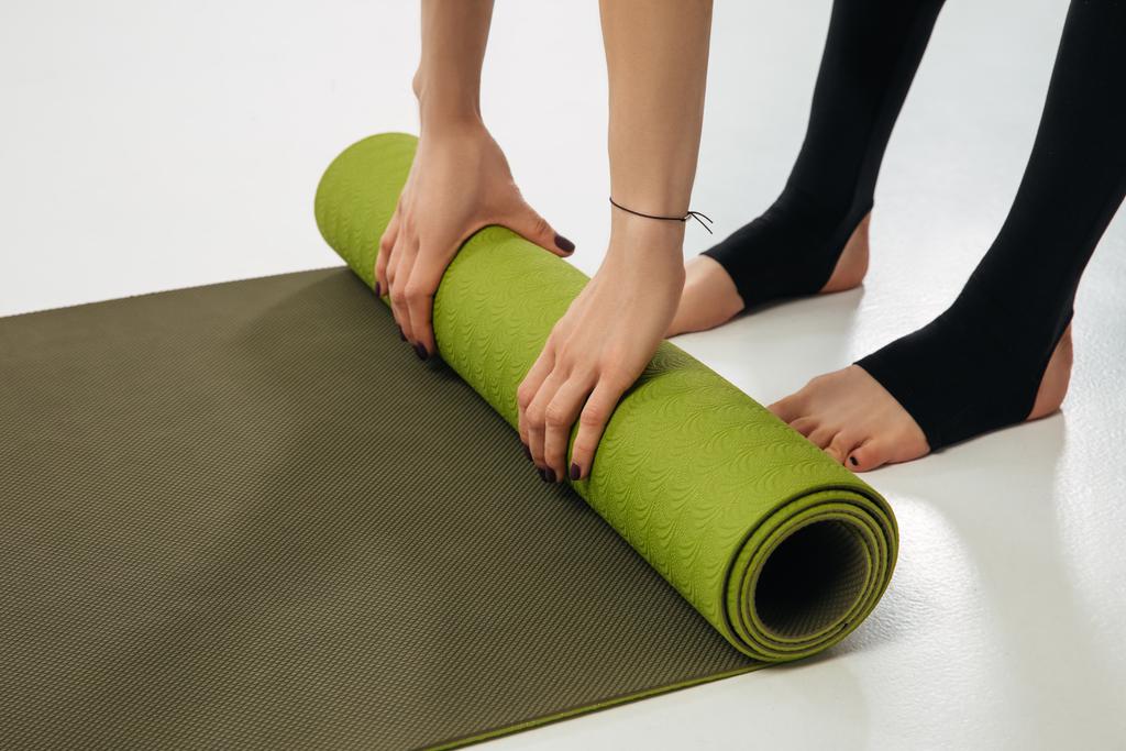abgeschnittenes Bild einer Frau, die Yogamatte auf den Boden legt - Foto, Bild