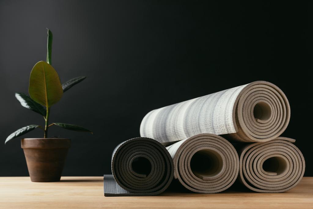 différents tapis de yoga roulés et plantes en pot sur une table en bois
 - Photo, image