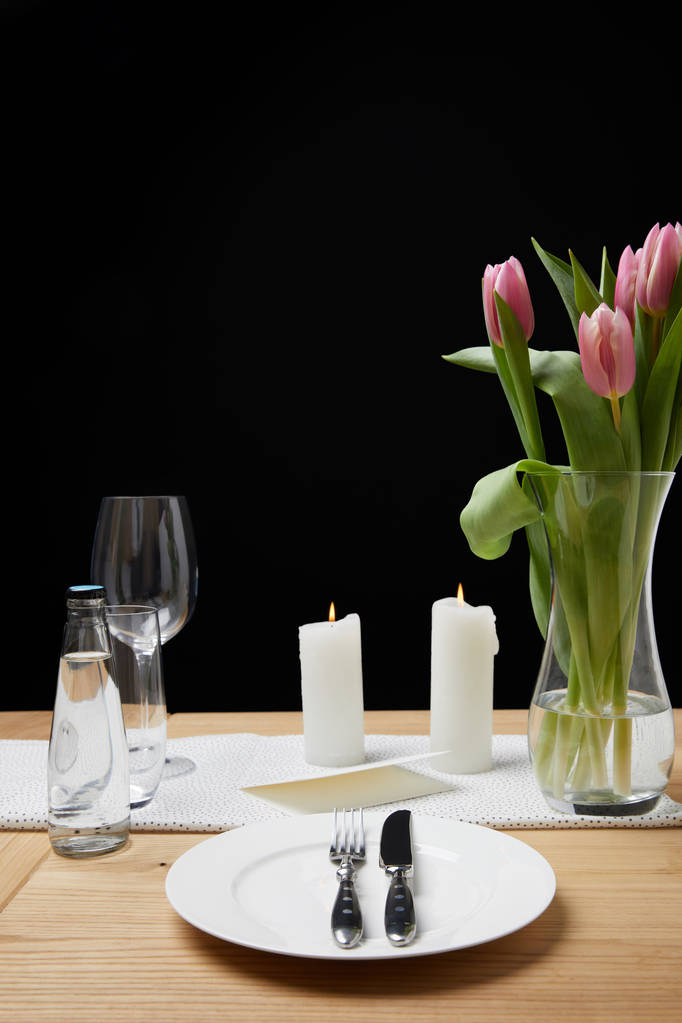 Florero con ramo de flores y velas en la mesa con vajilla festiva
 - Foto, imagen