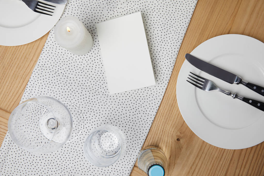Mesa festiva con cubiertos en platos sobre mesa con tarjeta en blanco
 - Foto, imagen