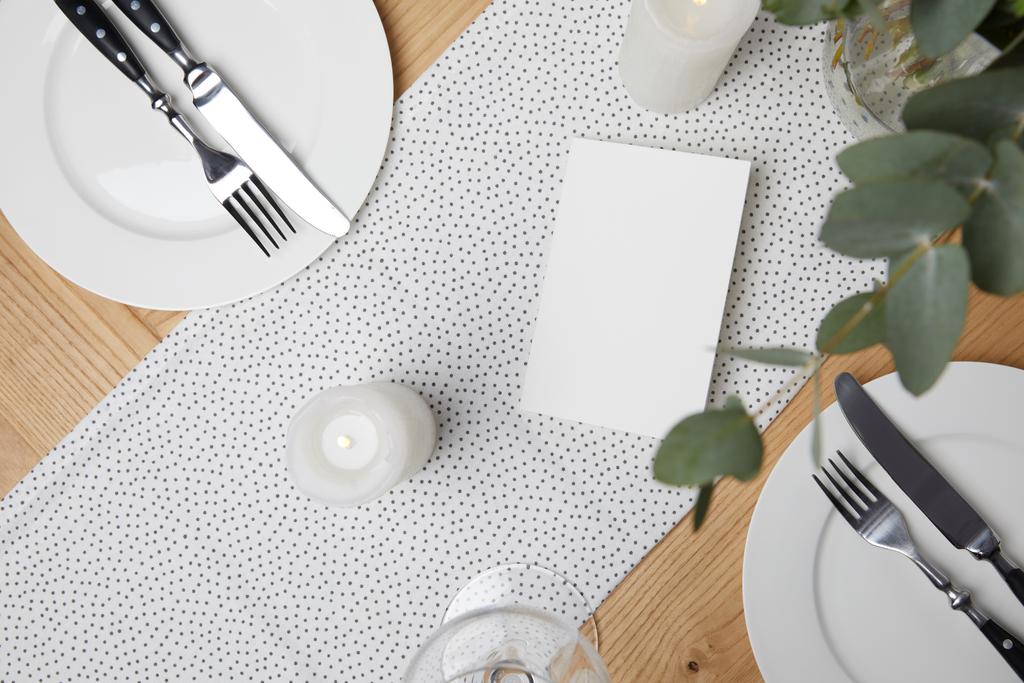 Feestelijke tafel met bestek op platen op tafel met kaarsen - Foto, afbeelding