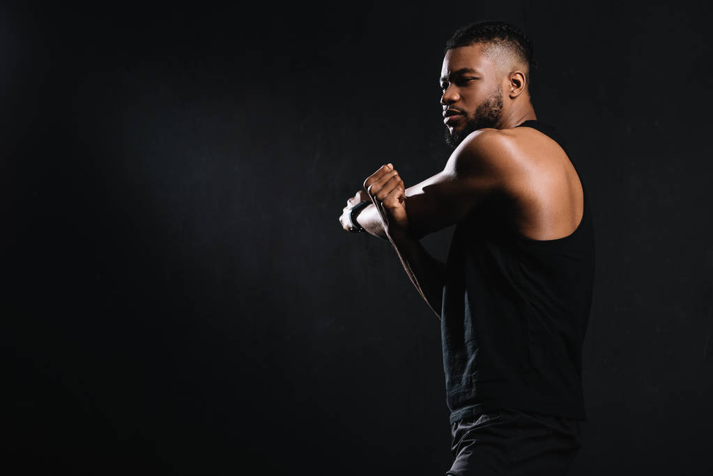 黒に分離された筋肉のストレッチ運動の若いアフリカ系アメリカ人の側面図 - 写真・画像