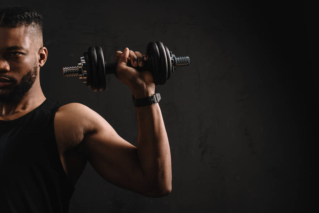 обрізаний знімок м'язистого афроамериканця тренування з гантелі ізольовані на чорному
 - Фото, зображення