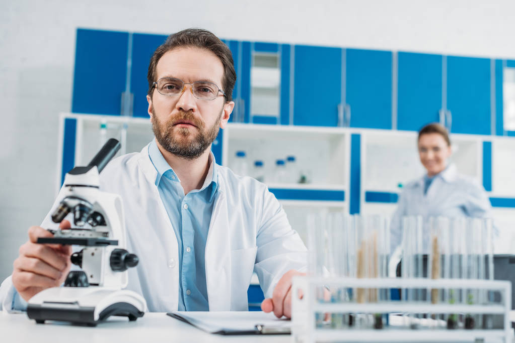 foyer sélectif du scientifique en manteau blanc et lunettes sur le lieu de travail avec microscope en laboratoire
 - Photo, image
