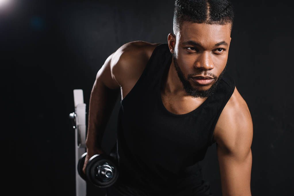 handsome young african american sportsman exercising with dumbbell in gym - Photo, Image