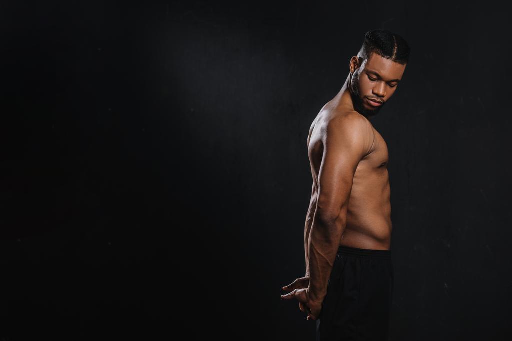 黒に分離された手を伸ばす筋肉の若いアフリカ系アメリカ人の側面図  - 写真・画像