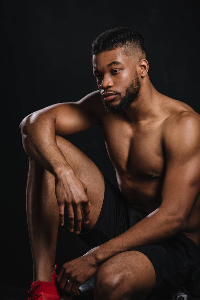 zamyślony shirtless młodego sportowca african american siedzi i szukasz drogi na czarny - Zdjęcie, obraz