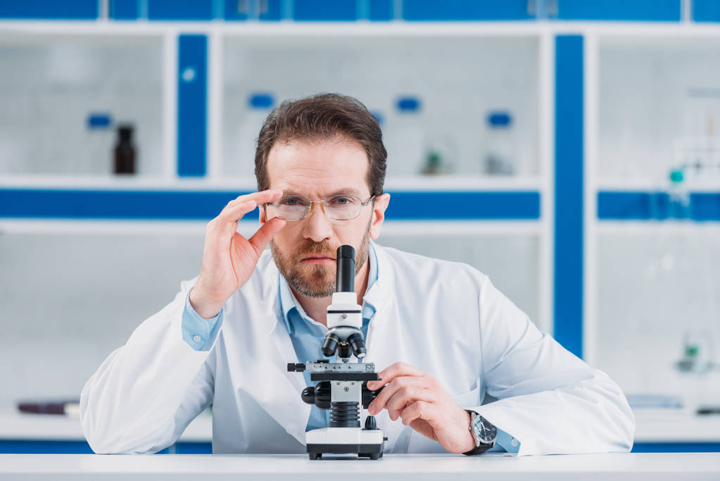 muotokuva tiedemies valkoinen takki ja silmälasit mikroskoopilla laboratoriossa
 - Valokuva, kuva