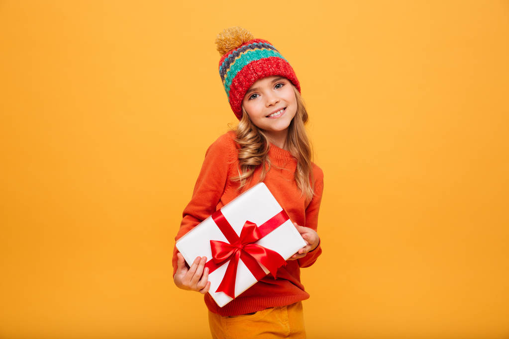Довольная молодая девушка в свитере и шляпе с подарочной коробкой
 - Фото, изображение
