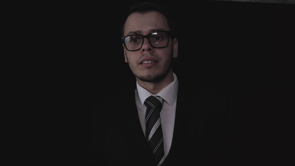 Portrét pohledný mladý podnikatel v brýlích, oblek, černé pozadí. - Fotografie, Obrázek