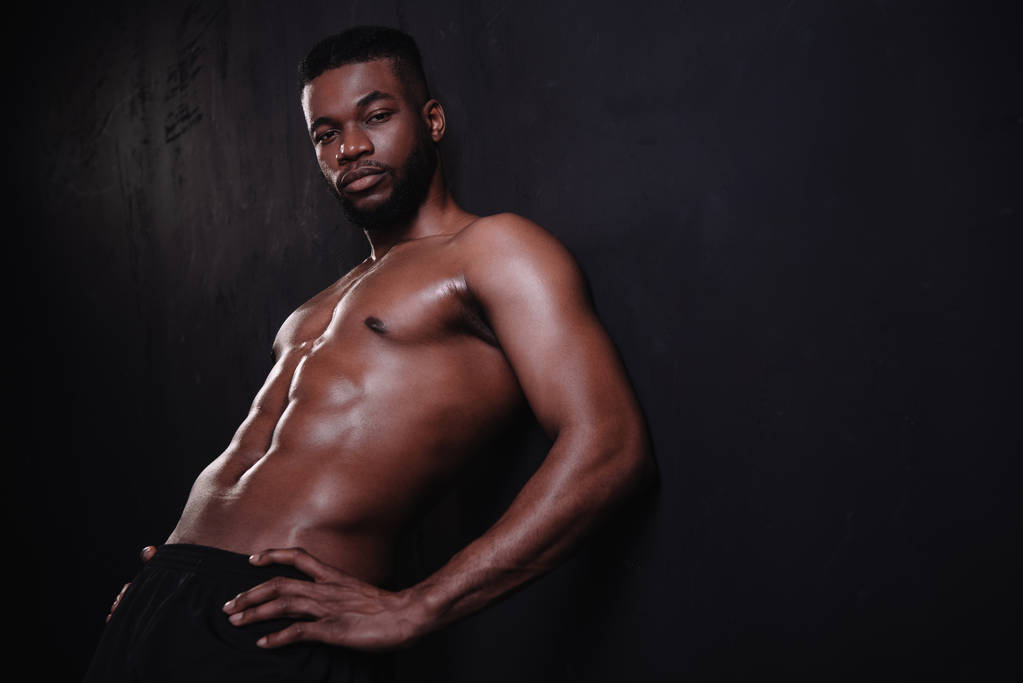 bonito sem camisa muscular afro-americano homem olhando para câmera no preto
  - Foto, Imagem