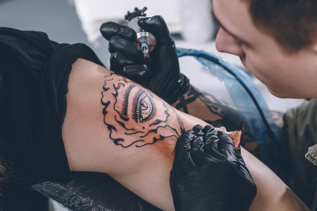Tattoo kunstenaar in handschoenen werken in studio - Foto, afbeelding