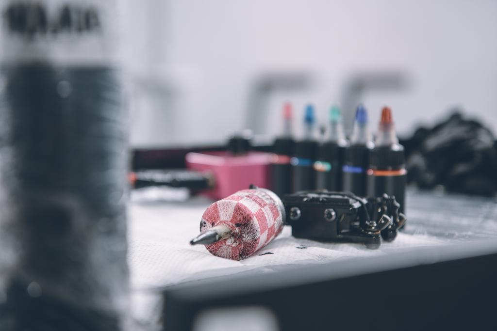 Botellas con tinta colorida del tatuaje y máquina en la mesa
 - Foto, Imagen