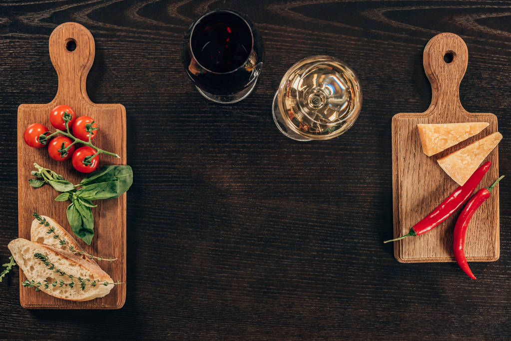 Blick von oben auf Gläser mit Wein und Parmesan mit Gemüse auf dem Tisch - Foto, Bild
