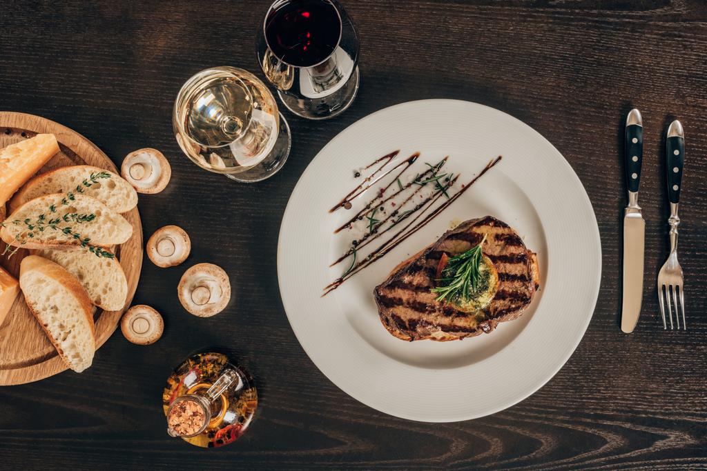 вид зверху на яловичий стейк, багет і вино на столі
 - Фото, зображення