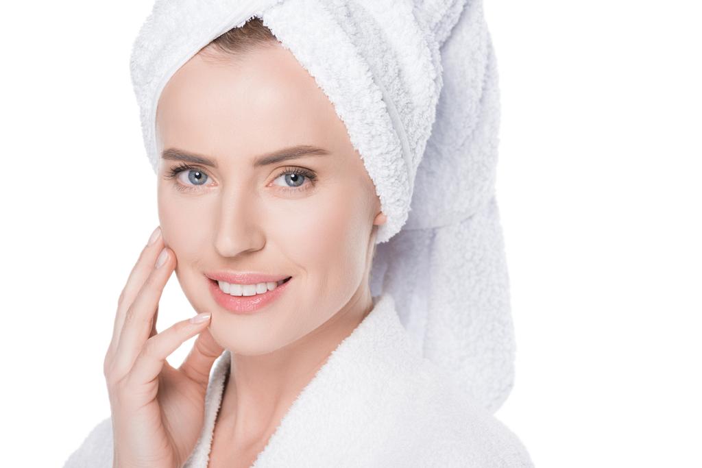 Mujer con la piel limpia en albornoz y toalla en el cabello tocando su propia cara aislada en blanco
  - Foto, imagen