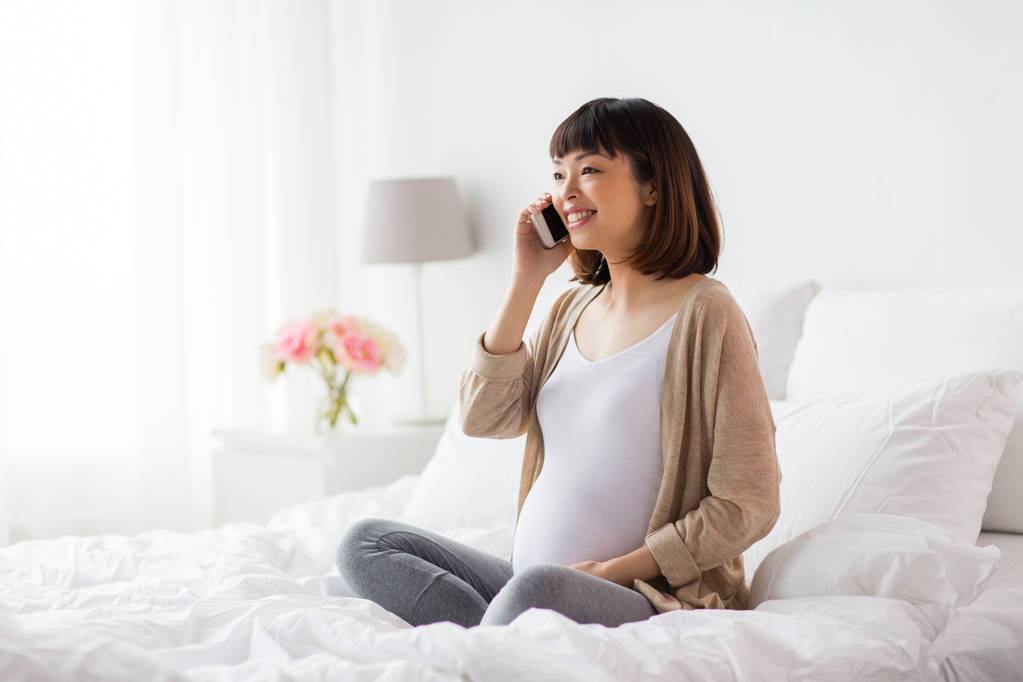 幸せな妊婦さんが自宅でスマホを呼び - 写真・画像