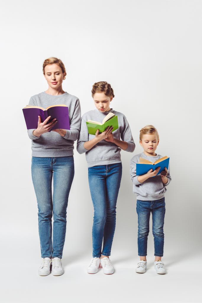 matki i córki w podobnych ubrań, czytanie książek na szarym tle - Zdjęcie, obraz