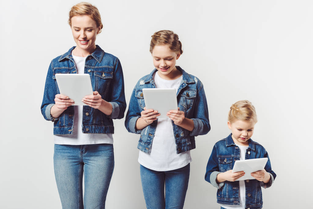 matka a dcery v podobných Džínové Oblečení stojí v řadě a použití tablet izolované Grey - Fotografie, Obrázek