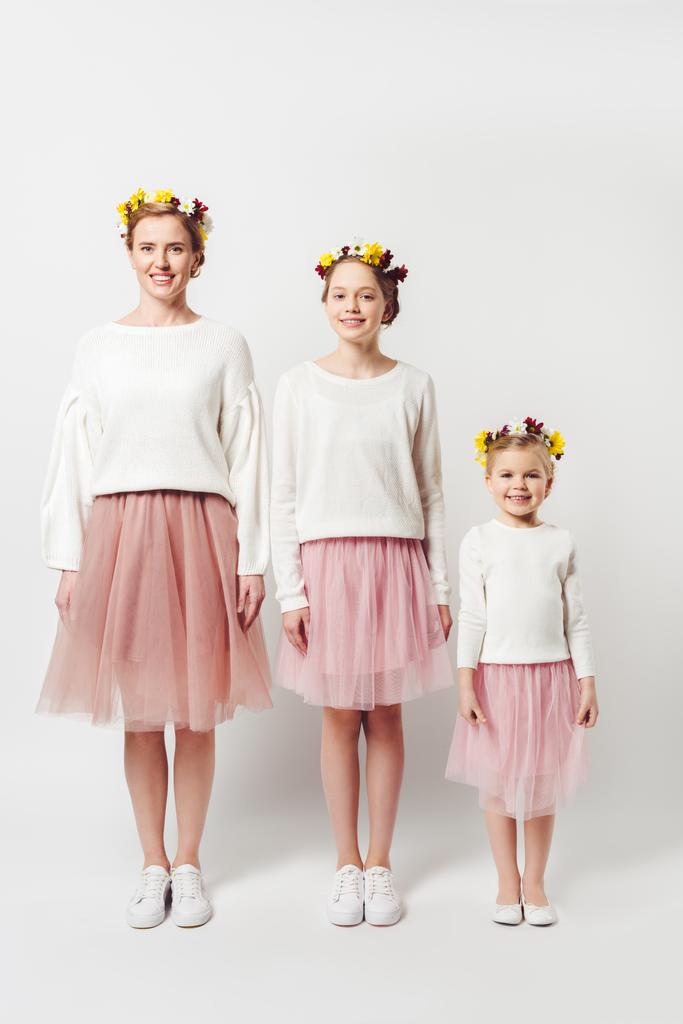 hermosa madre e hijas en ropa similar con coronas florales en cabezas aisladas en gris
 - Foto, imagen