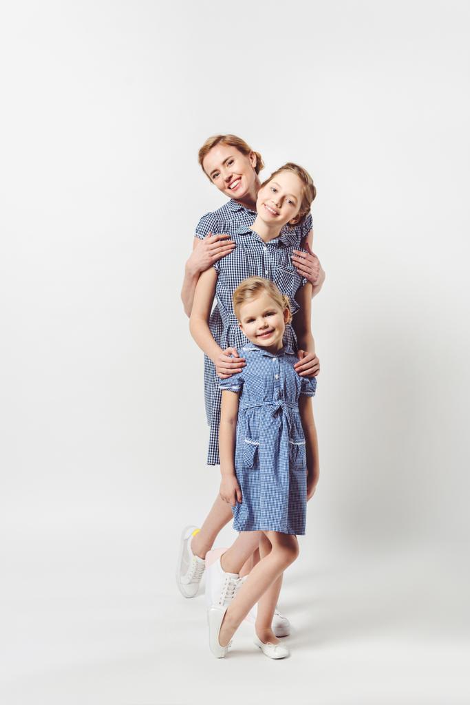 smiling mother and daughters in similar dresses isolated on grey - Photo, Image