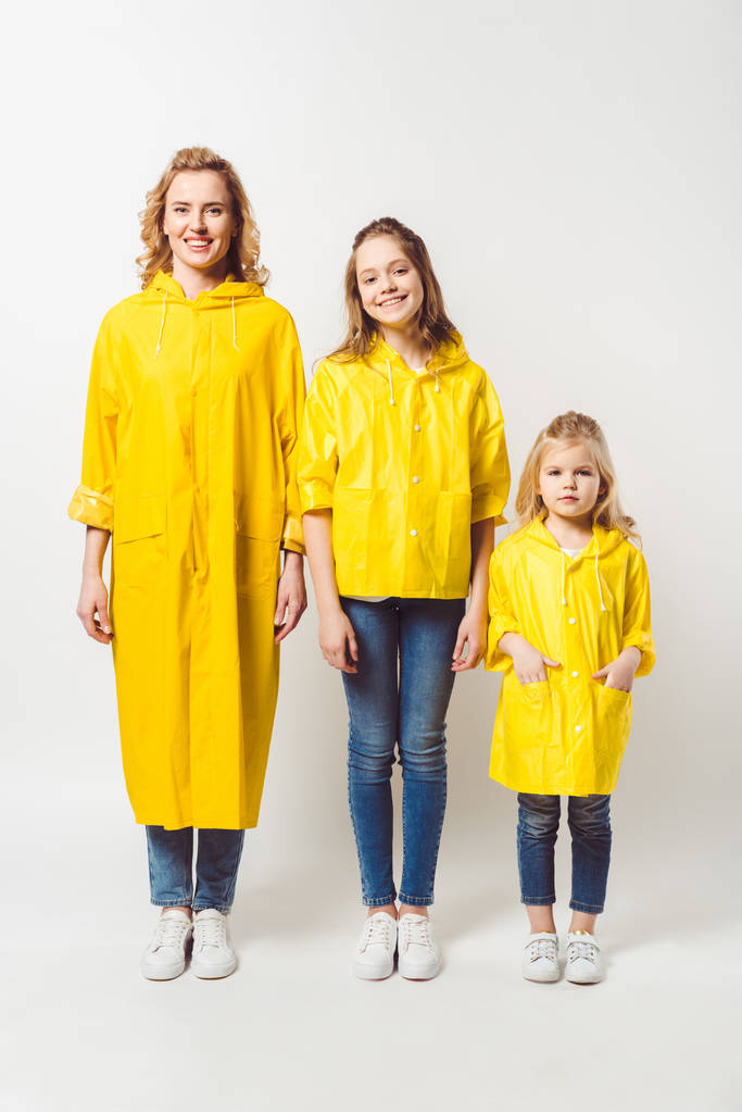 mother and daughters in yellow raincoats on white - Photo, Image