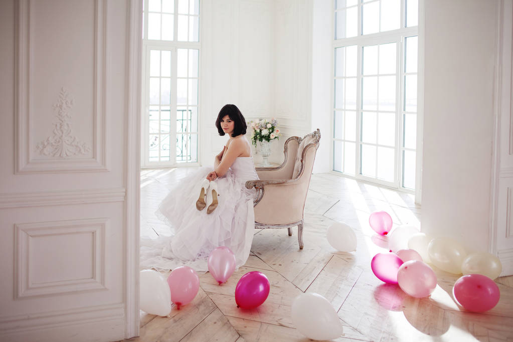 Νεαρή γυναίκα στο νυφικό στο πολυτελές εσωτερικό με μια μάζα των ροζ και λευκά μπαλόνια. - Φωτογραφία, εικόνα