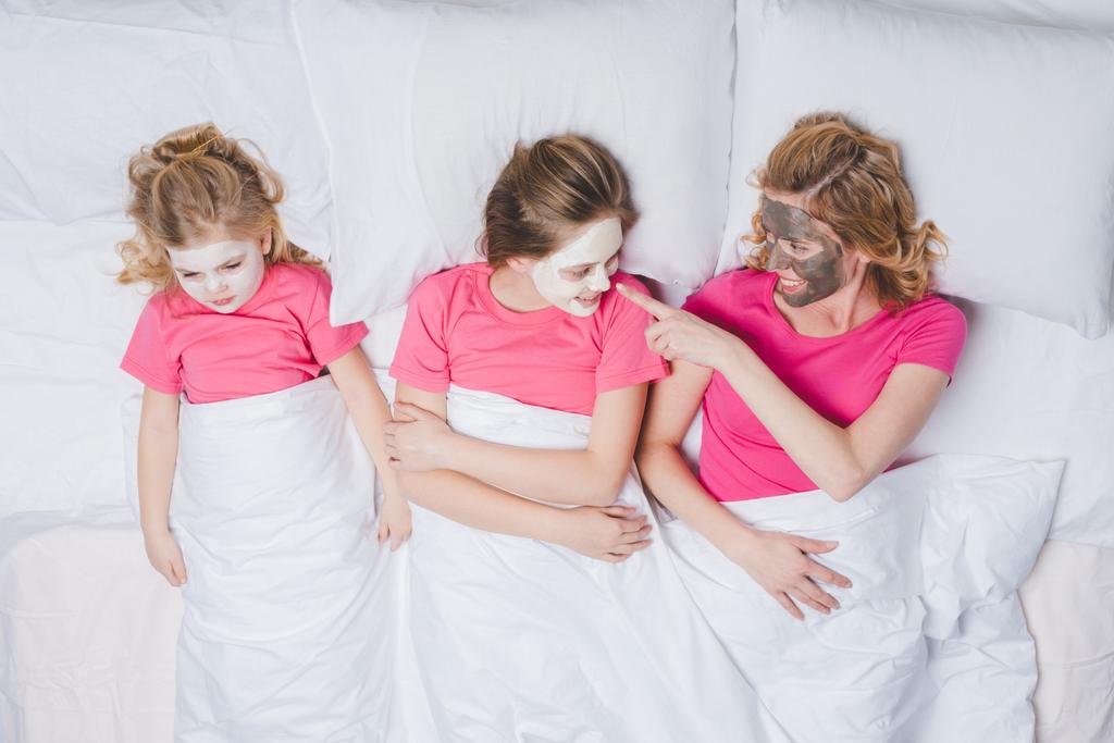 mutlu anne ve kızları ile birlikte cilt bakım maskeleri yatakta yatan bir Üstten Görünüm  - Fotoğraf, Görsel