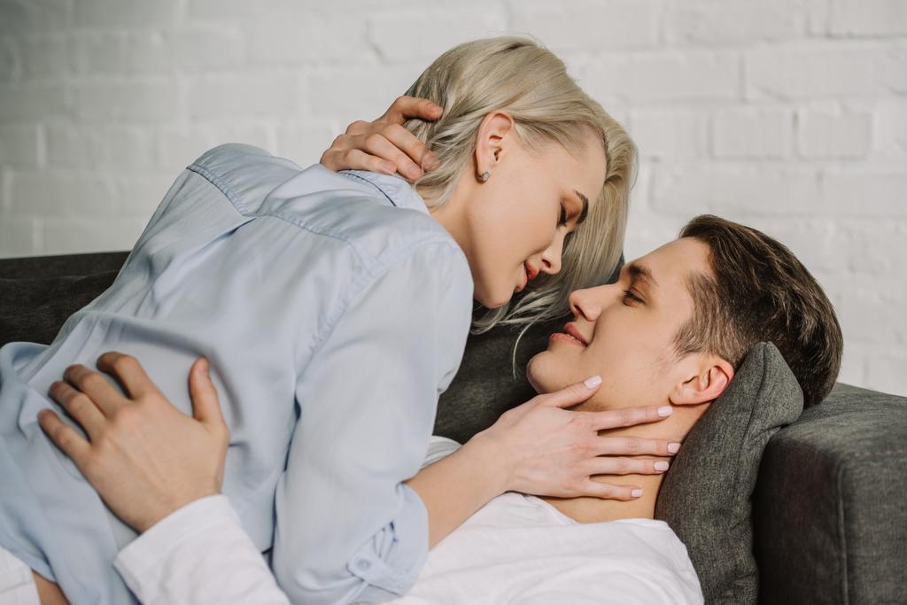 сексуальна пара лежить на дивані і обіймається вдома
 - Фото, зображення