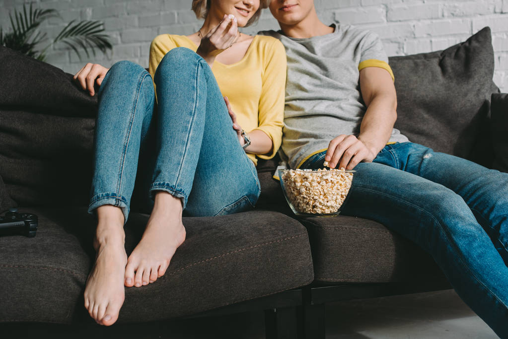 immagine ritagliata di coppia seduta sul divano con popcorn
 - Foto, immagini
