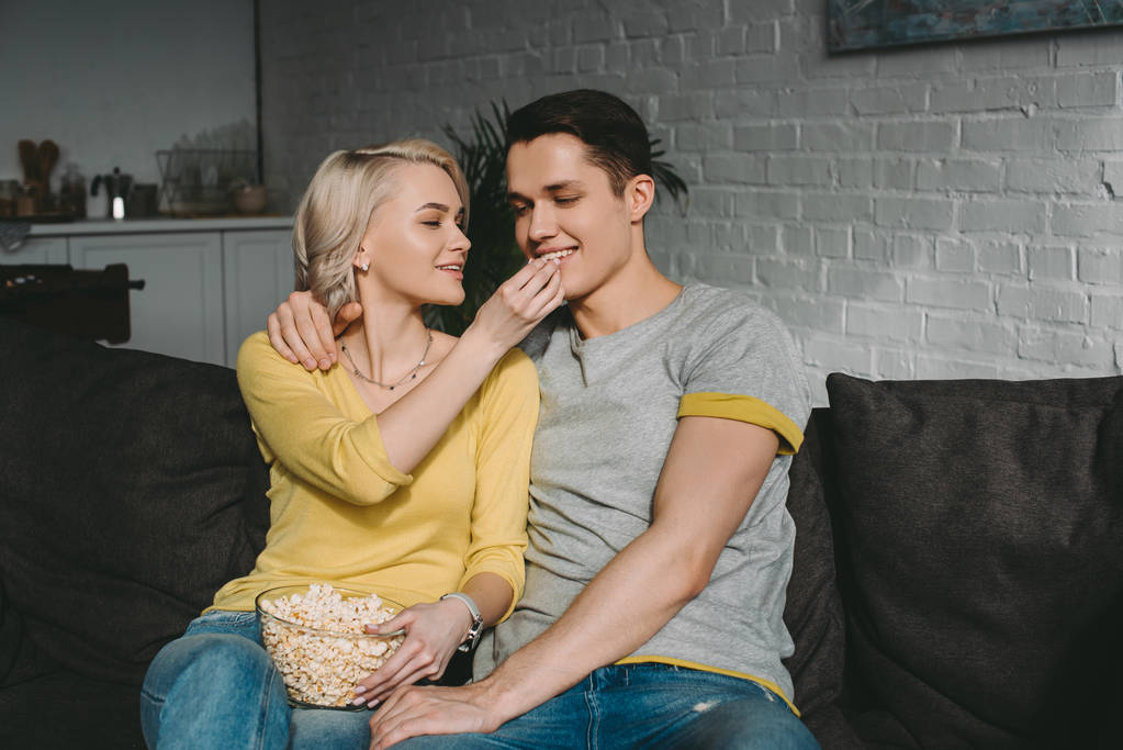 smiling girlfriend feeding boyfriend with popcorn - Photo, Image