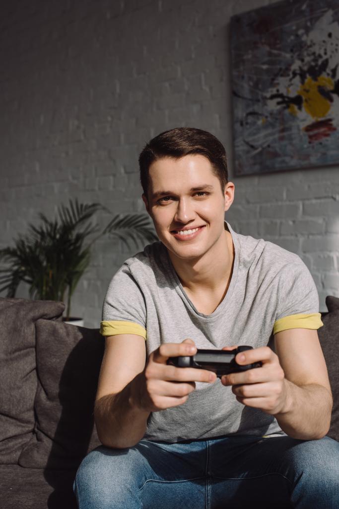 handsome man playing video game at home and looking at camera - Photo, Image