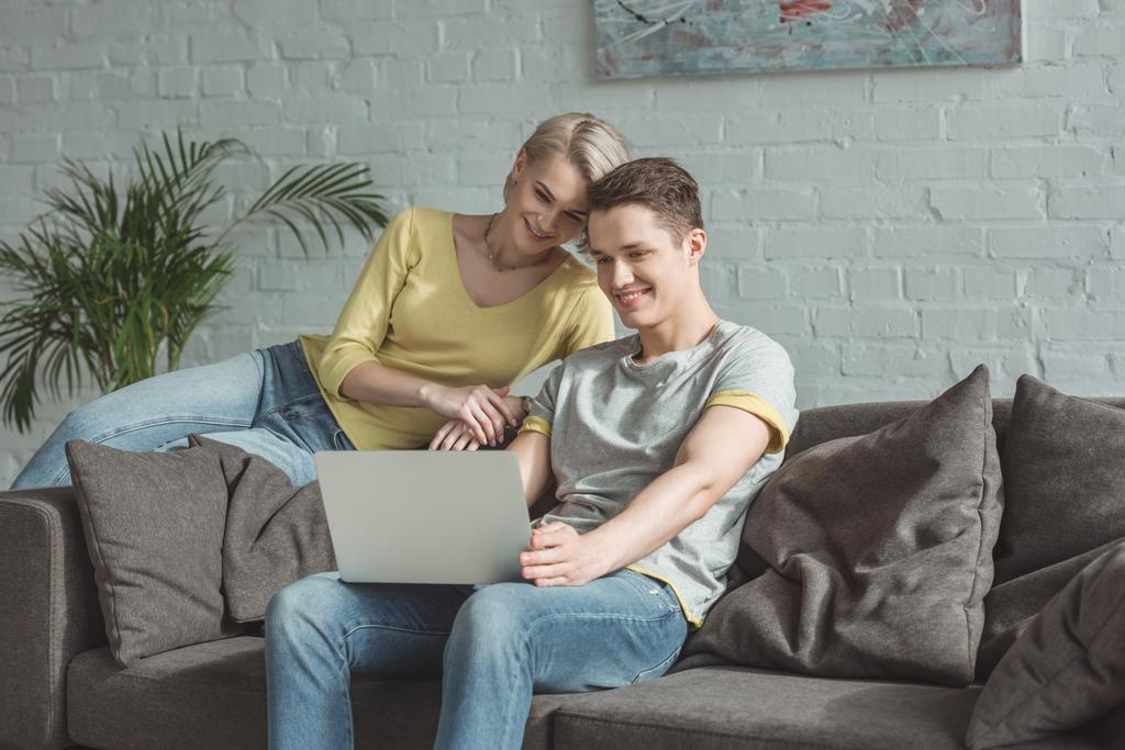 sonriente pareja mirando portátil en casa
 - Foto, Imagen