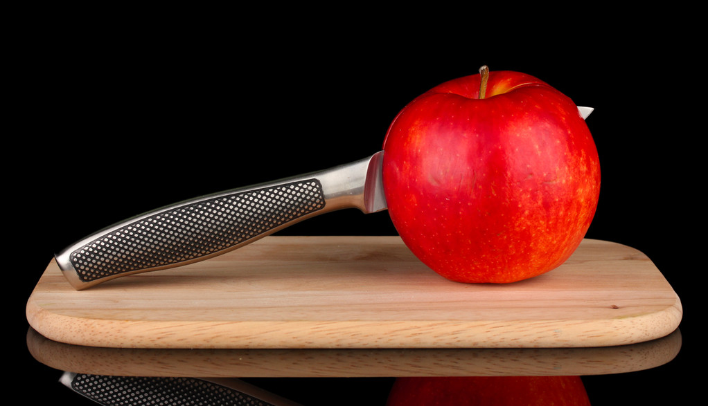 Pomme rouge et couteau sur planche à découper, isolés sur noir
 - Photo, image