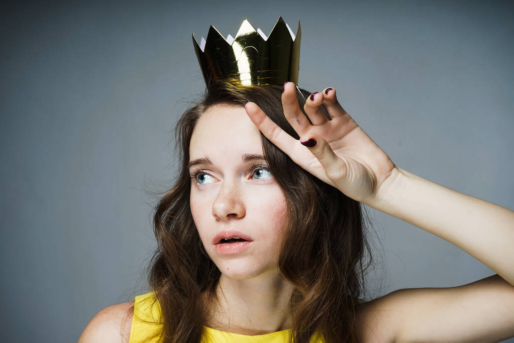 triest jonge vrouw in een jurk te wachten voor de dag van de vrouw van een wereld op haar hoofd een gouden kroon - Foto, afbeelding