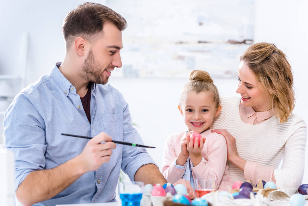 Child holding Easter egg by smiling parents - Photo, Image