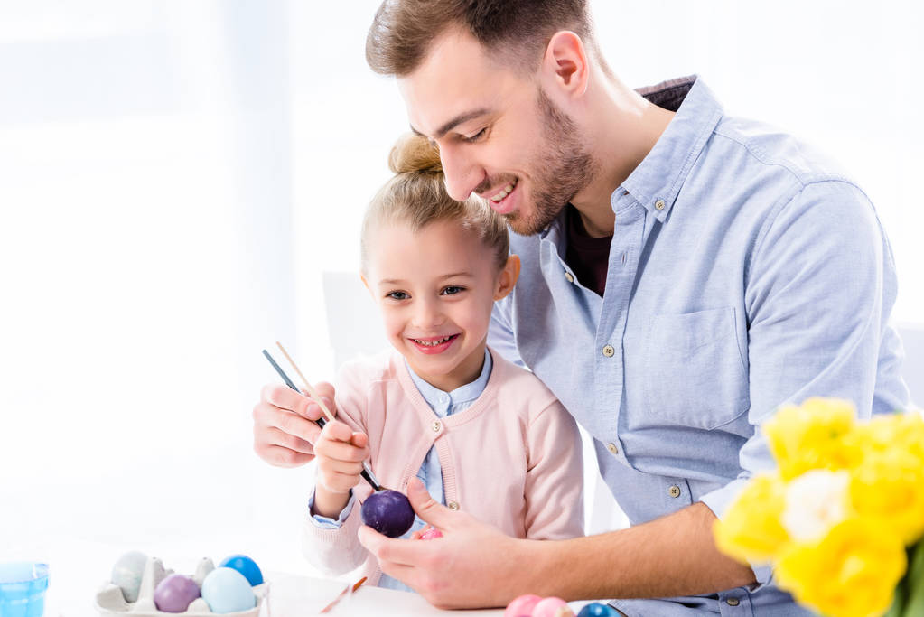 Батько допомагає дочці фарбувати великодні яйця
 - Фото, зображення