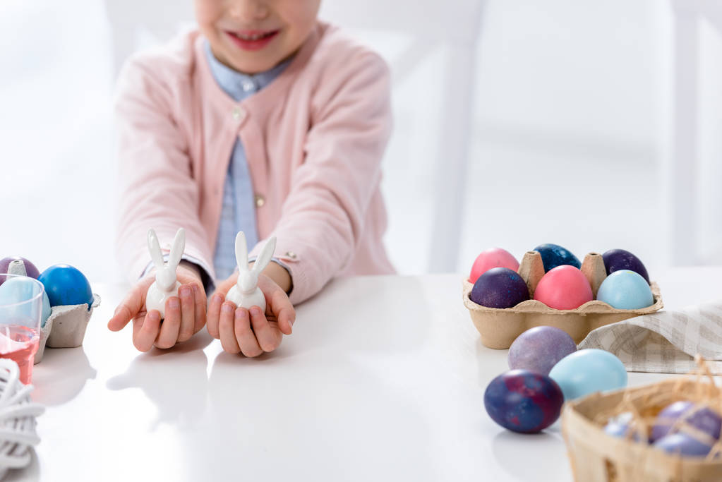 Vista close-up da criança na Páscoa segurando estatuetas de coelho por ovos pintados
 - Foto, Imagem