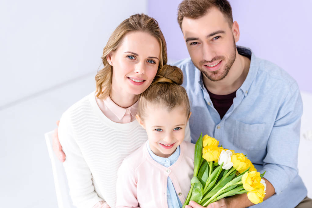 Roztomilé dítě a rodiče drží kytici tulipánů na 8 březen - Fotografie, Obrázek