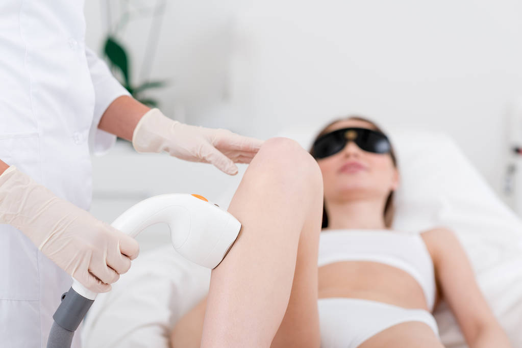Partielle Ansicht einer Frau, die im Salon eine Laser-Haarentfernung am Bein erhält - Foto, Bild