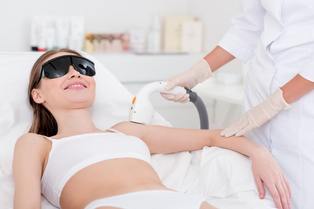 abgeschnittene Aufnahme einer Frau bei Laser-Haarentfernung am Arm im Salon - Foto, Bild