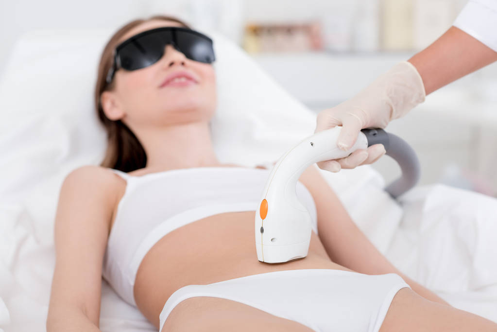 donna in biancheria intima che riceve la procedura di depilazione laser su stomaco su salone
 - Foto, immagini