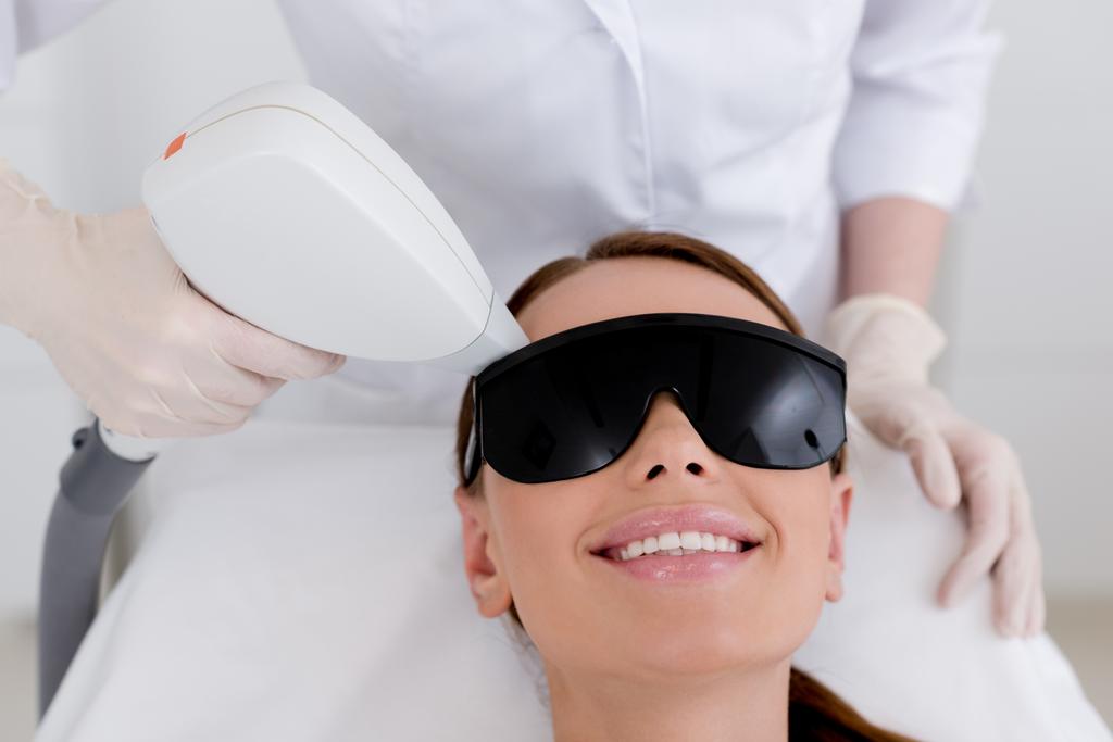 częściowy widok młoda kobieta odbiera laserowa epilacja usuwania włosów na twarzy w salonie - Zdjęcie, obraz