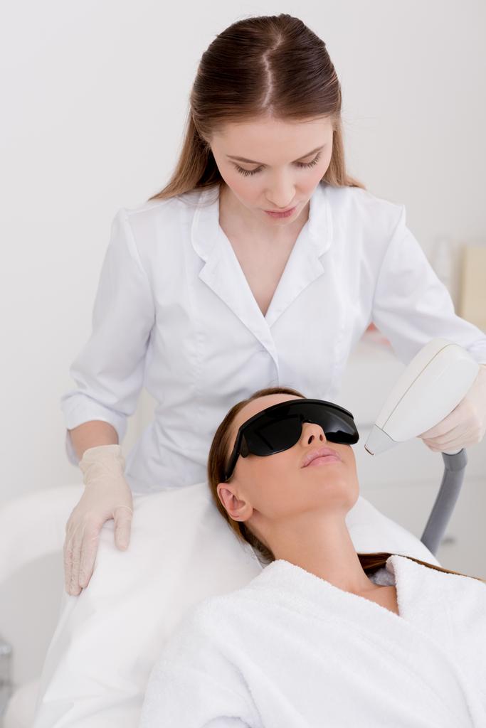 mujer joven consiguiendo procedimiento de depilación láser en la cara en el salón
 - Foto, imagen