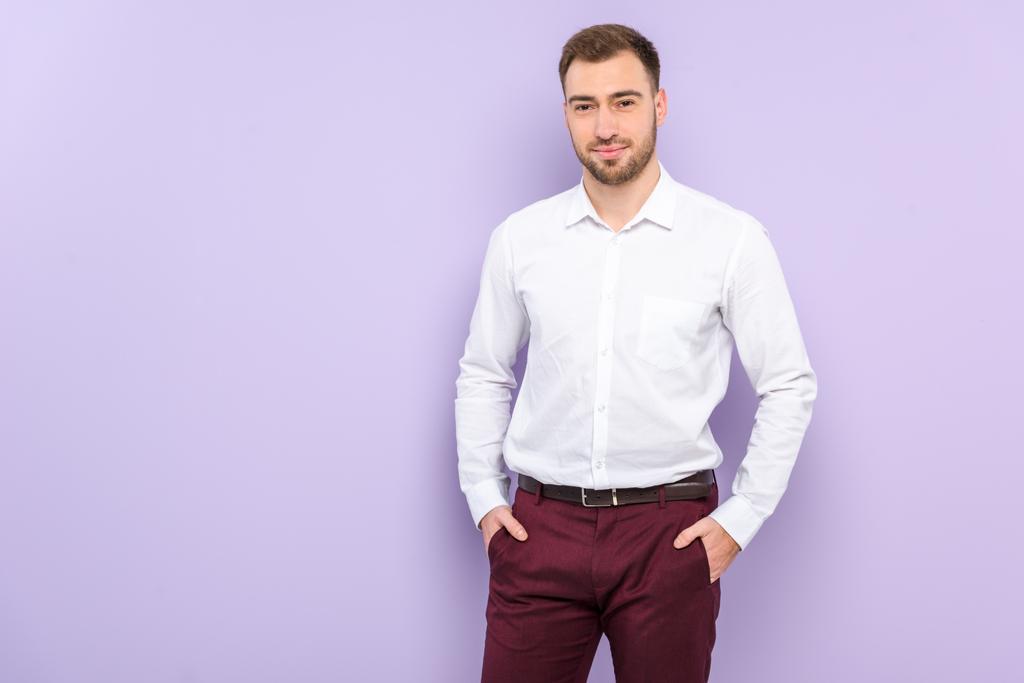 Violet izole ceplerinde gömlek ayakta eller ile giyen adam - Fotoğraf, Görsel