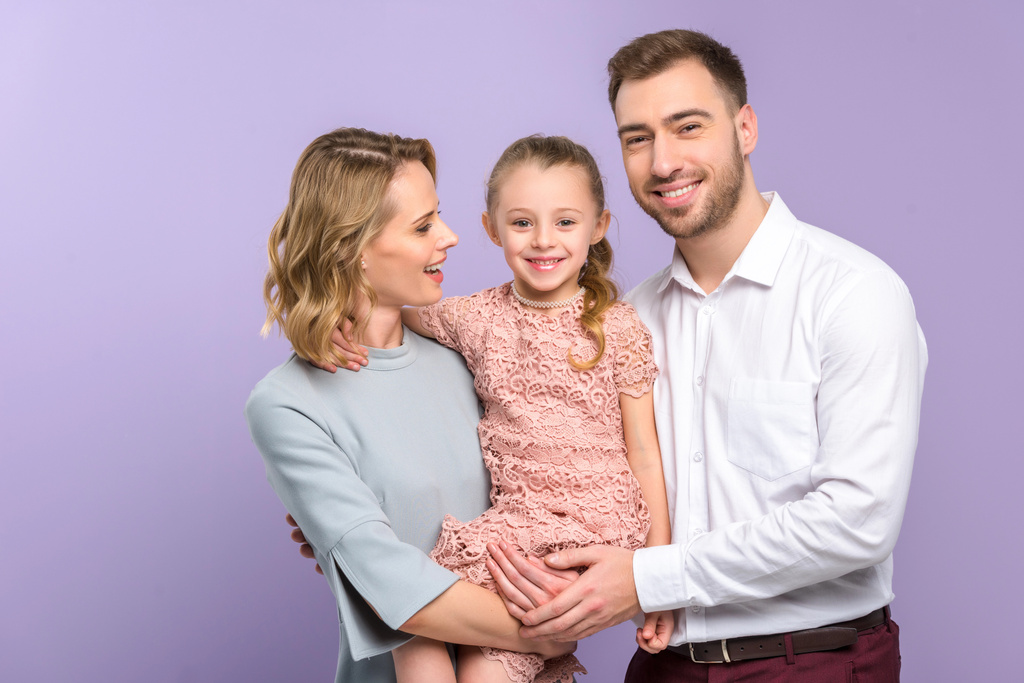 Adorable familia abrazando con hija en violeta fondo
 - Foto, Imagen